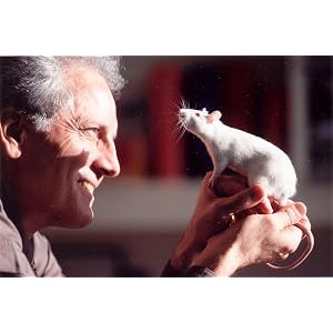 George Paxinos smiling warmly at a white laboratory rat perched on his hand